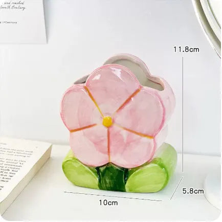 Ceramic pen holder box with floral pattern and lid on a wooden desk.