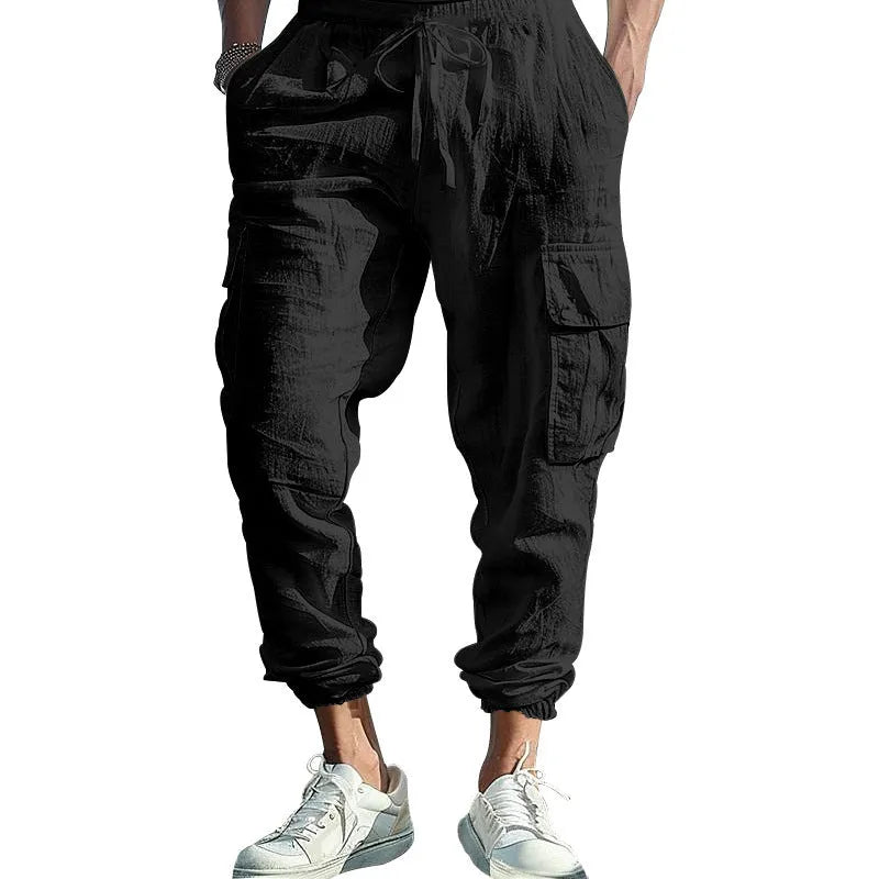 Man wearing loose-fit linen casual trousers with ankle-tied cuffs and multiple pockets in a solid colour.