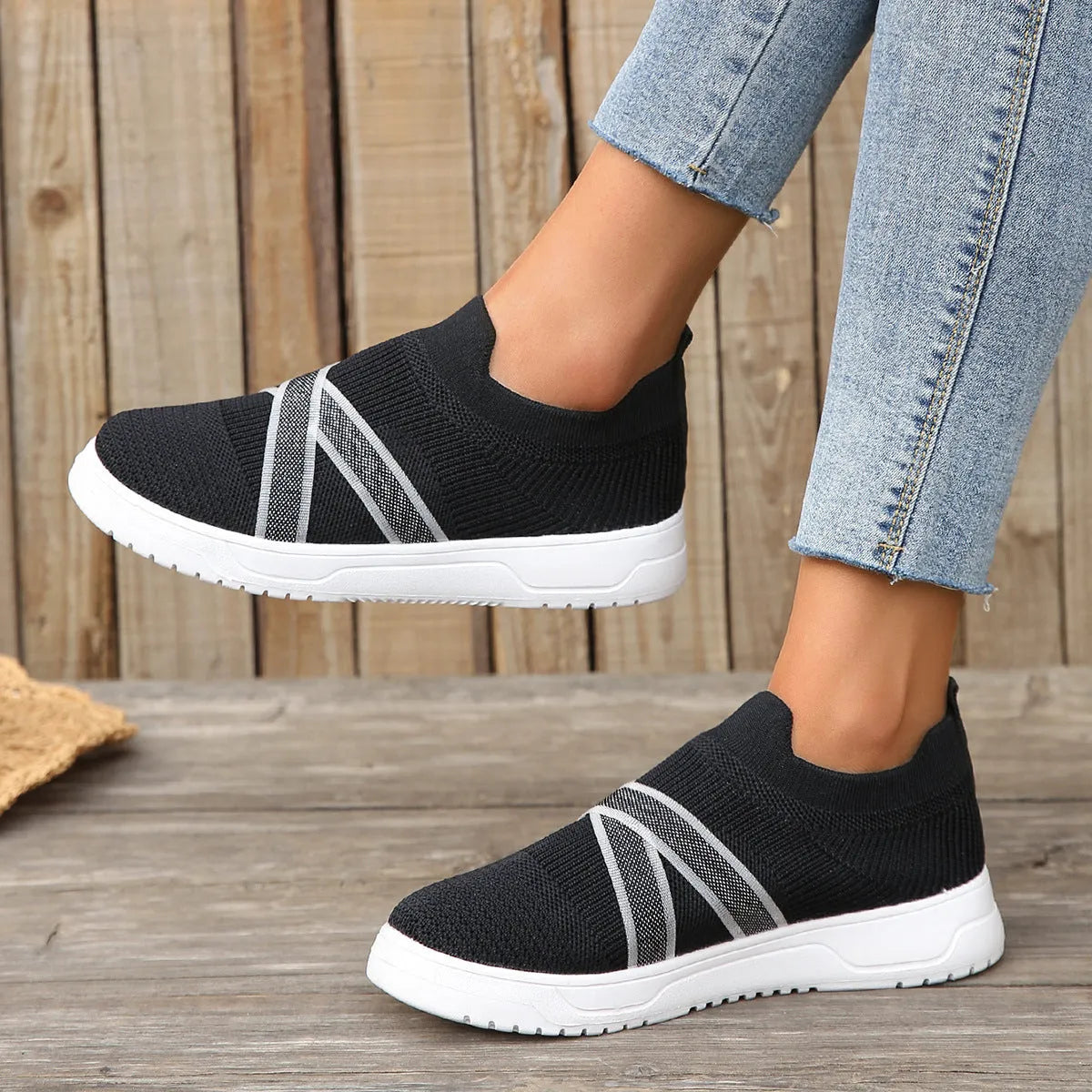 Black women's flyknit mesh casual shoes with a flat rubber sole and a tassel detail on the upper.