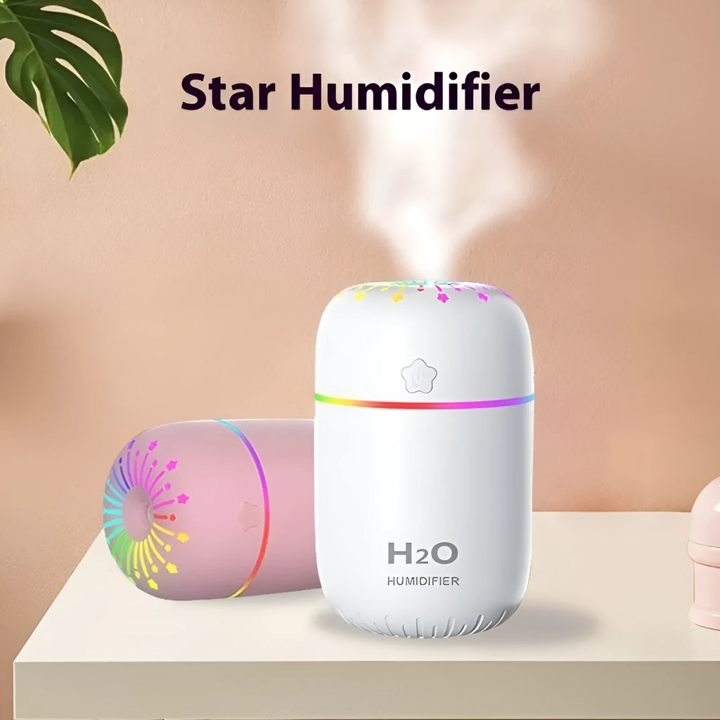 White USB personal mini humidifier with fireworks design on a wooden desk next to a laptop.