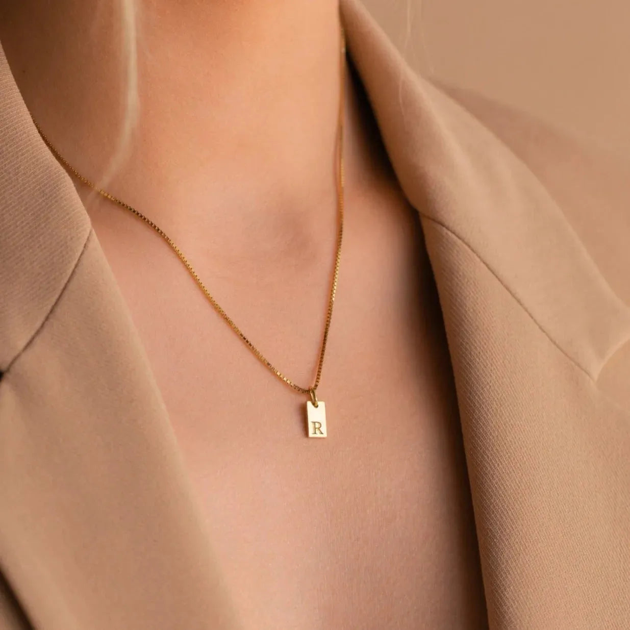 Mini square stainless steel initial necklace with gold plating on a sparkling box chain
