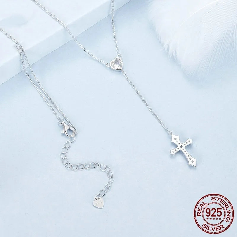 Close-up of a delicate silver love cross pendant on a thin O-ring chain, designed for V-neck wear.