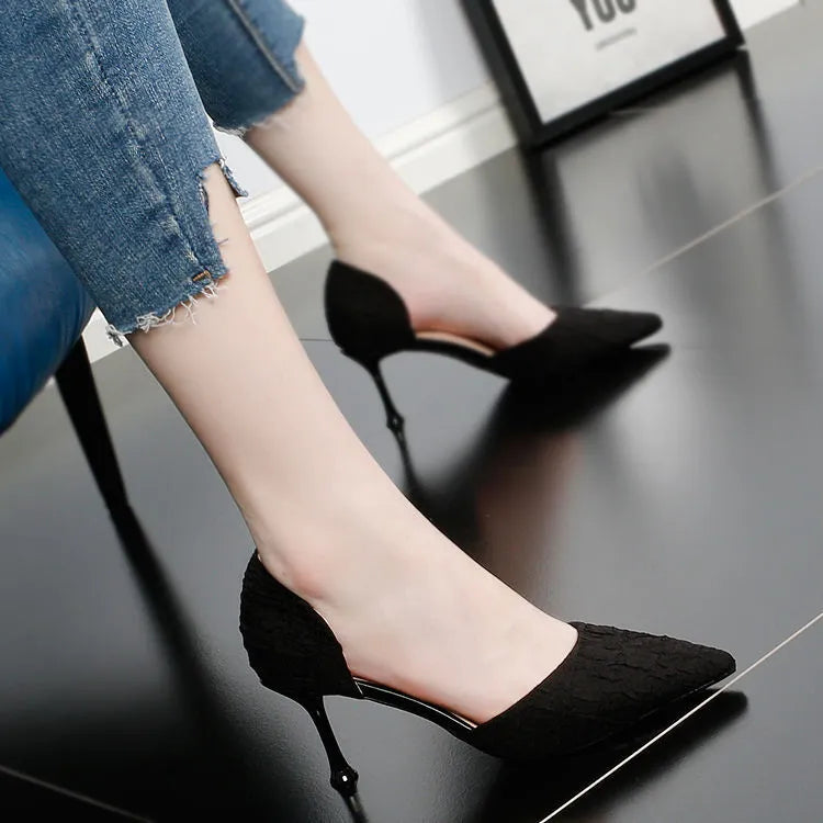 Women's black pointed toe stiletto high heels with a thin heel on a plain background.