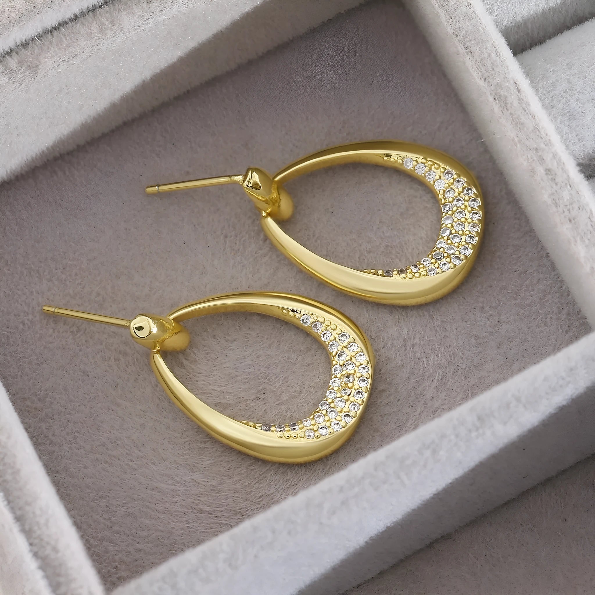 Yellow gold geometric drop earrings with oval and round ring elements on copper