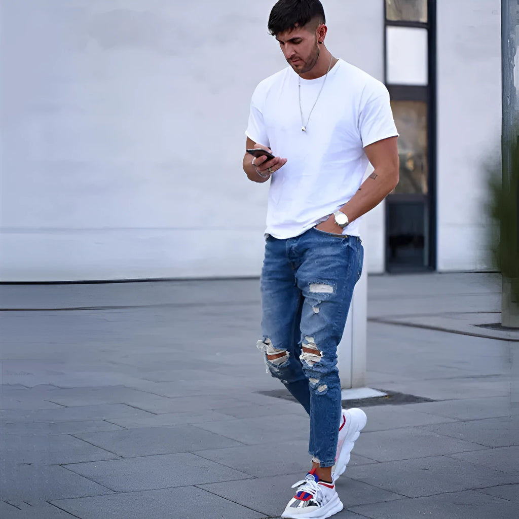 Men's deep blue jeans with distressed hole detailing on cotton denim fabric