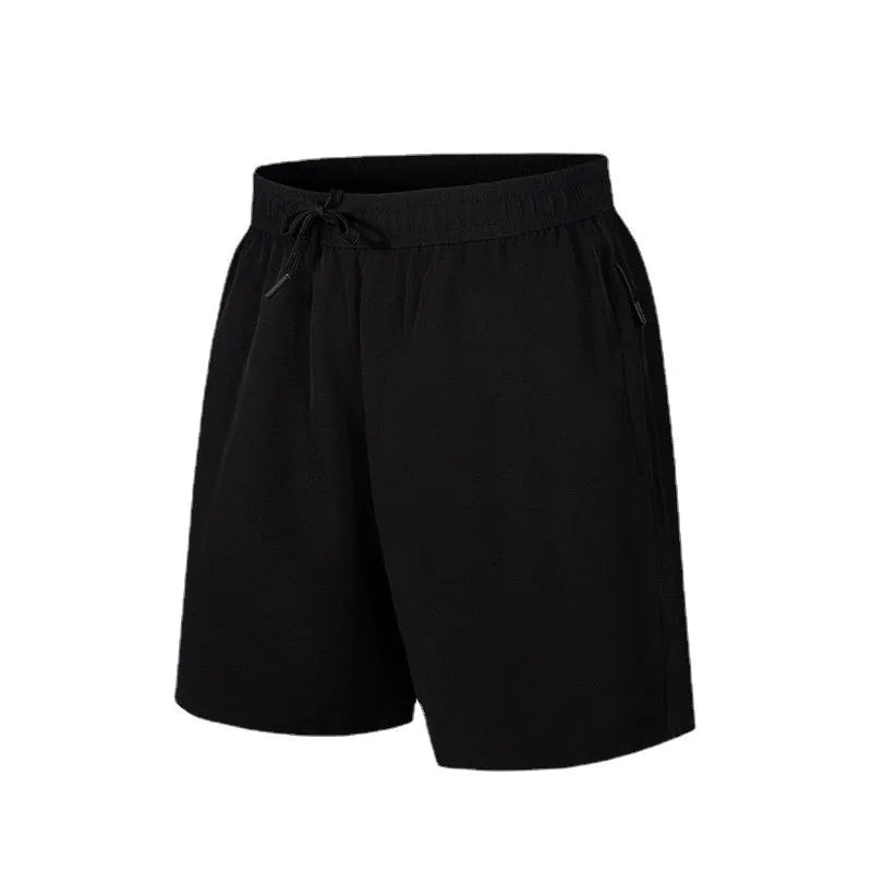 Man wearing loose fit black quick-dry sports shorts on a beach.