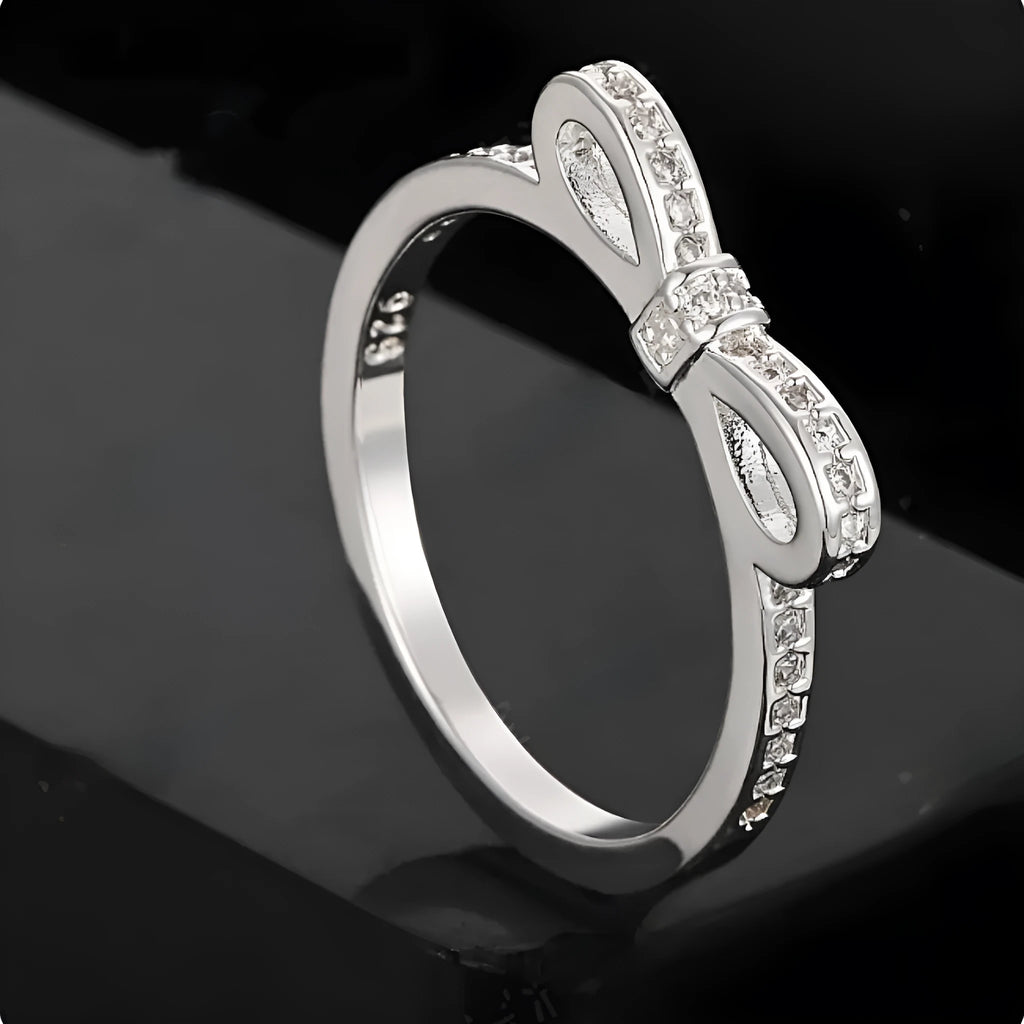 Silver bow-shaped ring with rhinestone zircon crystal detailing showing side profile view