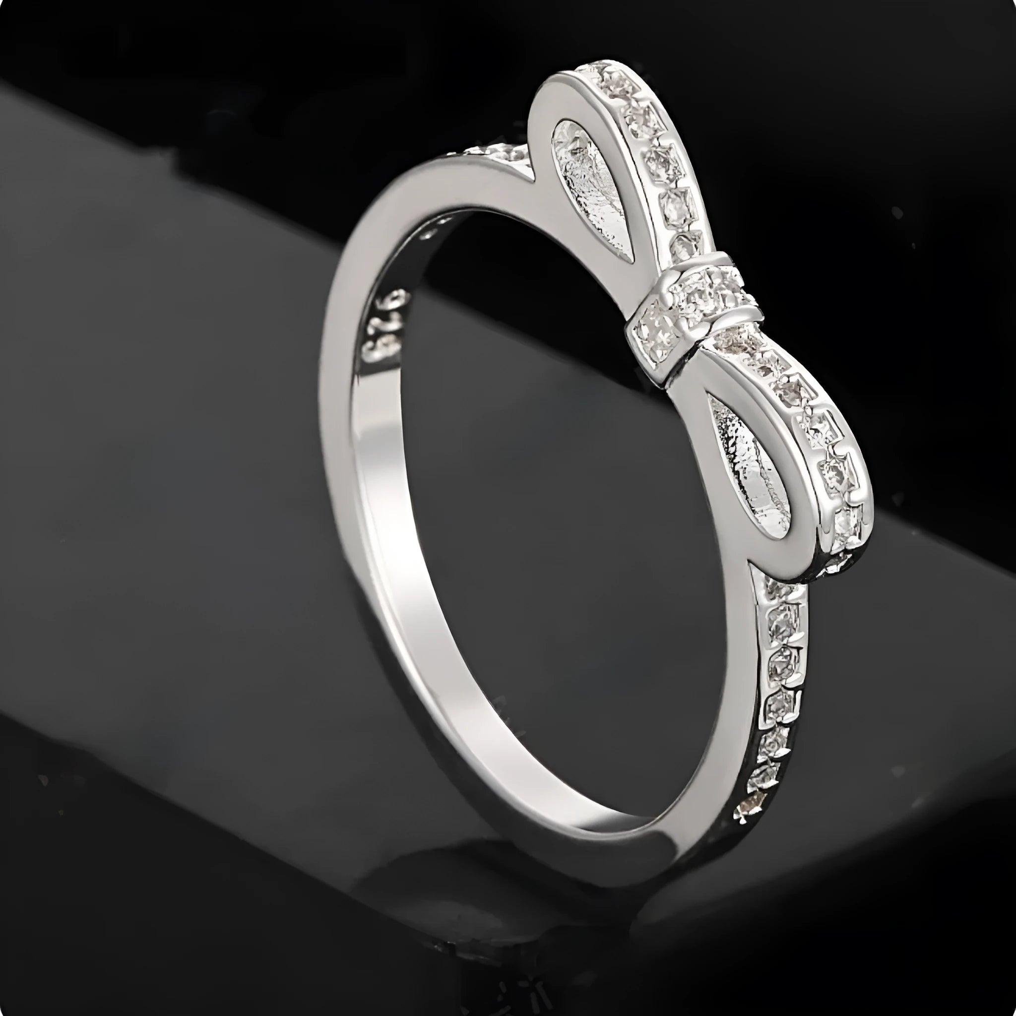 Silver bow-shaped ring with rhinestone zircon crystal detailing showing side profile view