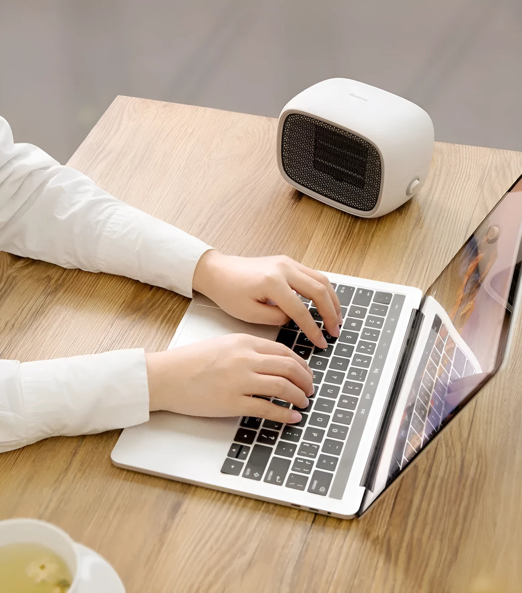 Green, white and yellow mini personal space heater on a desk showing compact size.