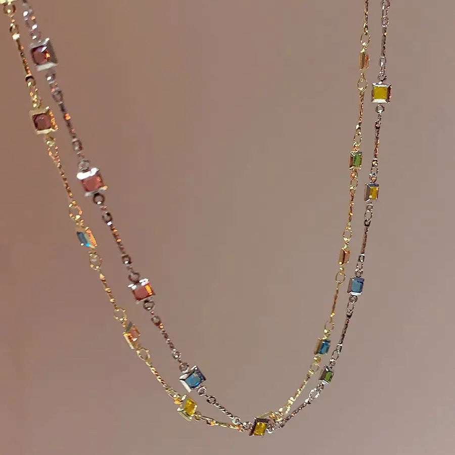 Square geometric clavicle chain necklace in gold tone with artificial crystal details on a model.