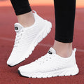 Women's running shoes in black, pink, or white with a woven fly knit upper and textured outsole.