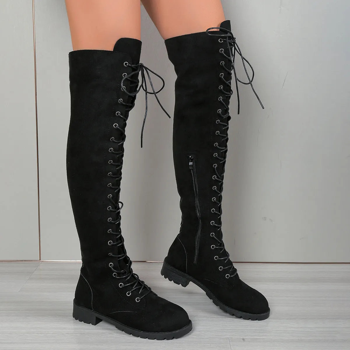 Women's black lace-up over-the-knee boots with round toe and flat rubber sole on a neutral background.