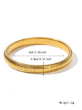 Close-up of a women's titanium steel bracelet with a vertical stripe ring pattern, shown in a gold tone finish on a wrist.