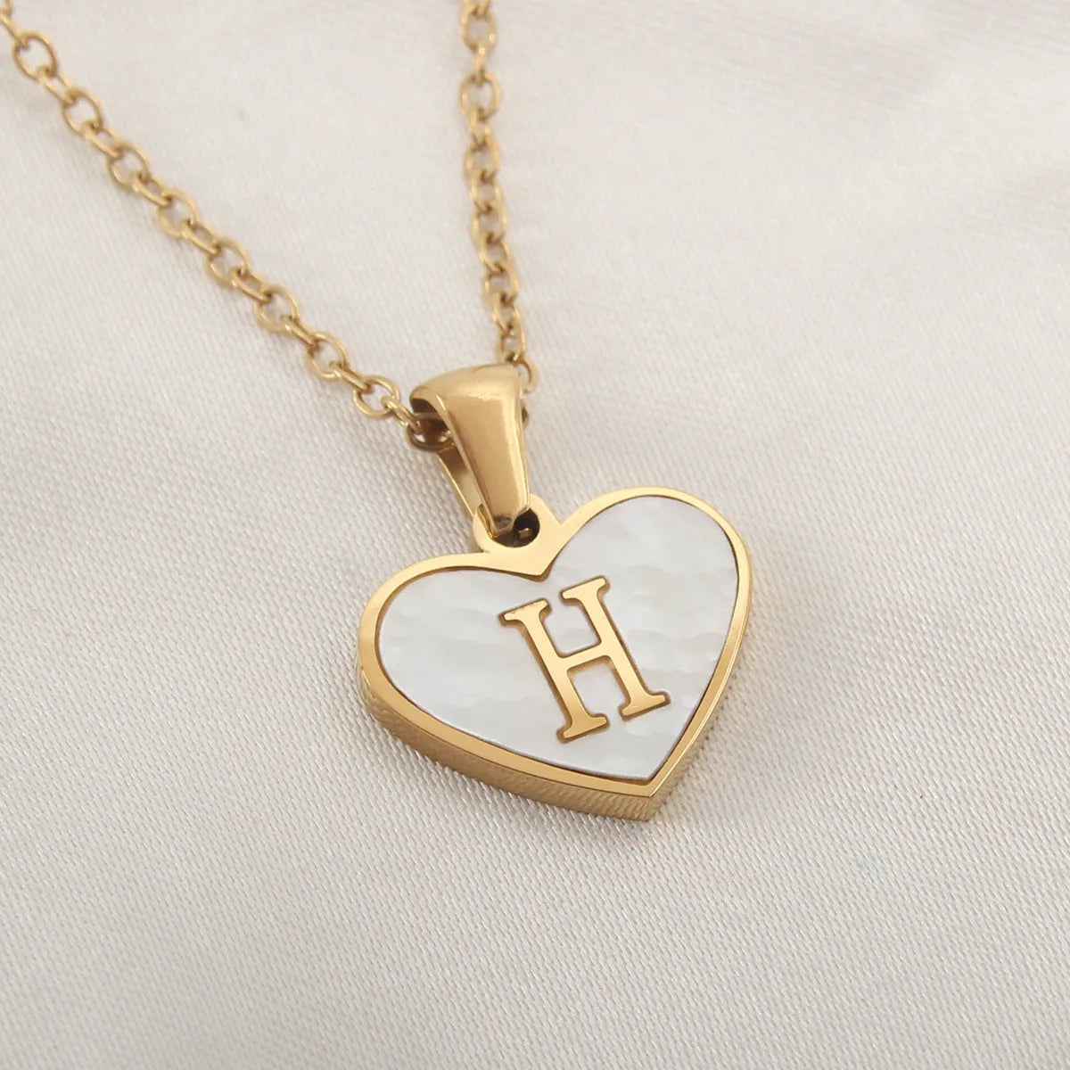 Gold heart necklace with white shell detail and personalised initial letter on adjustable chain