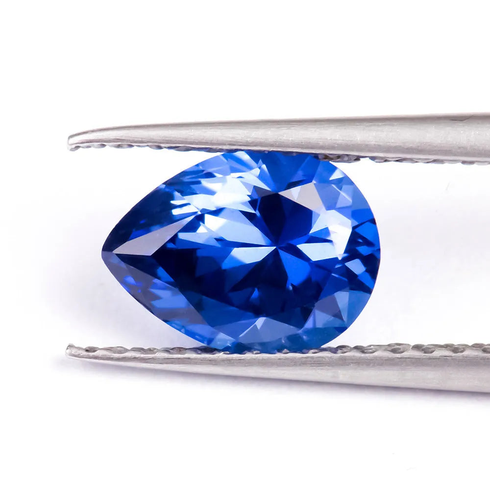Royal blue loose cultured gemstone in heart, round, and pear shapes on a grey background.
