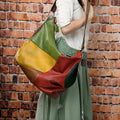 Brown cowhide leather travel bag with stitching detail, shown with a laptop and worn crossbody.