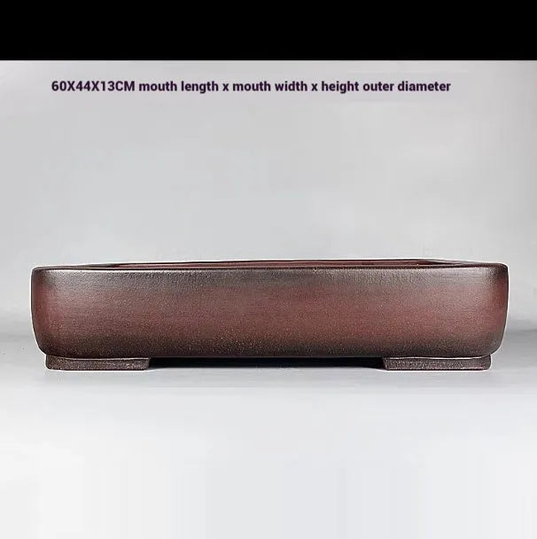 Handmade antique-style rectangular purple clay flower pot on a wooden surface.