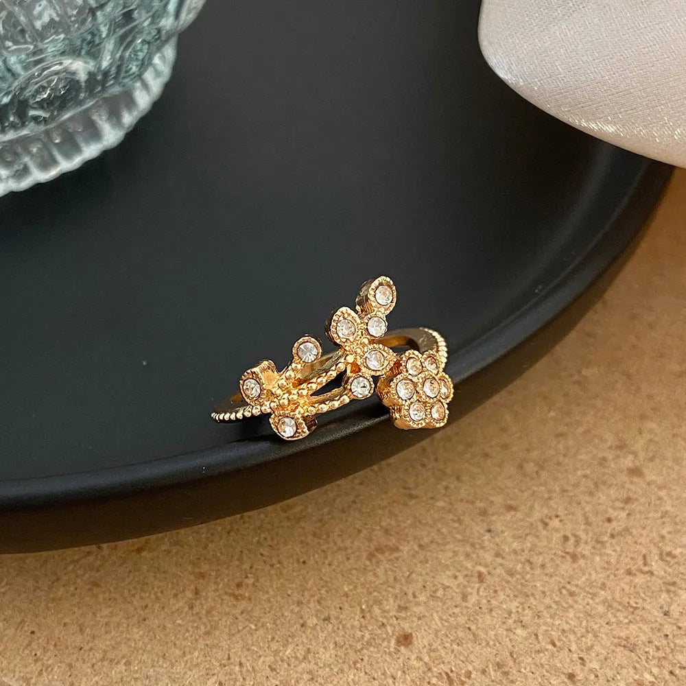 Women's open ring with diamond flower and leaf pattern in copper, shown in gold and white colour options.