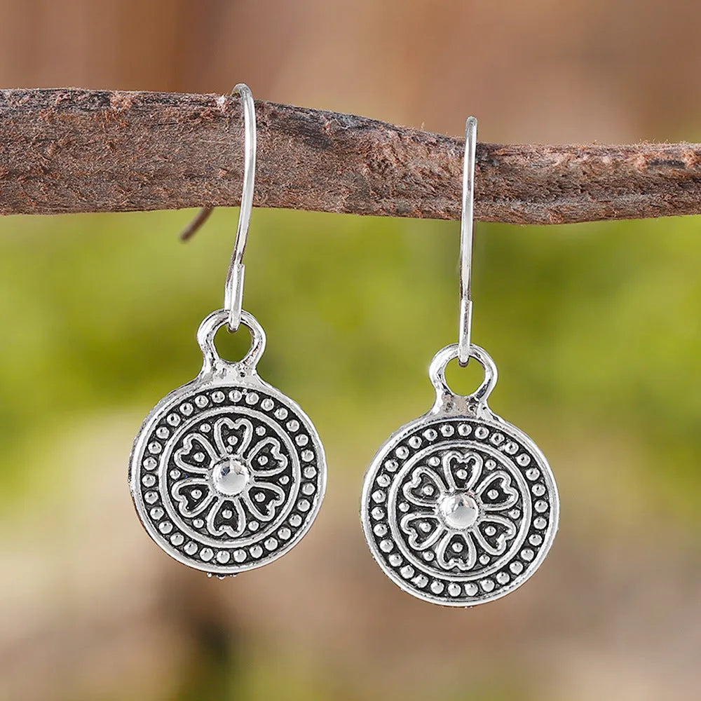 A pair of bohemian retro geometric earrings with a distressed finish and round elements.