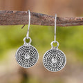 A pair of bohemian retro geometric earrings with a distressed finish and round elements.