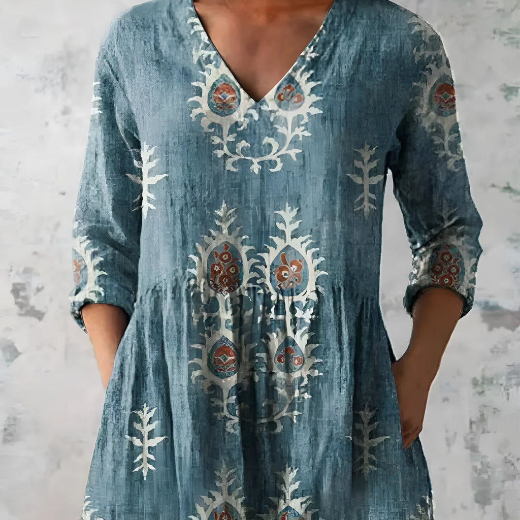 A woman modelling a printed, loose-fitting dress with a wide waist and three-quarter length sleeves.