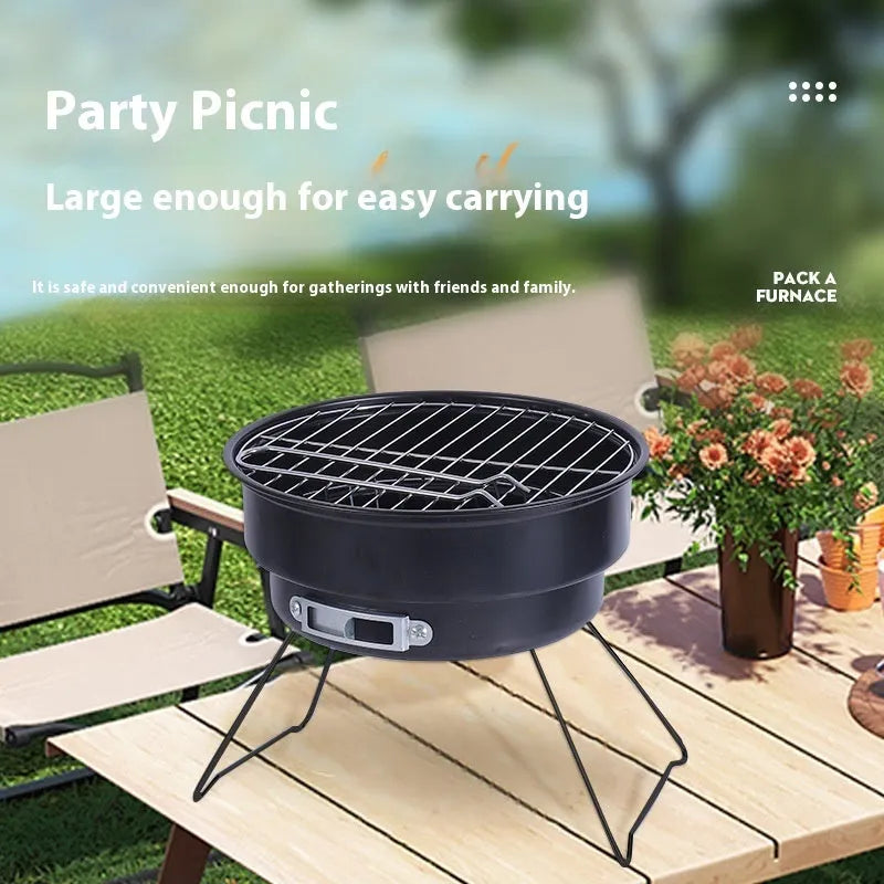 Small metal folding outdoor charcoal stove with mesh grill and tripod legs set up on grass.
