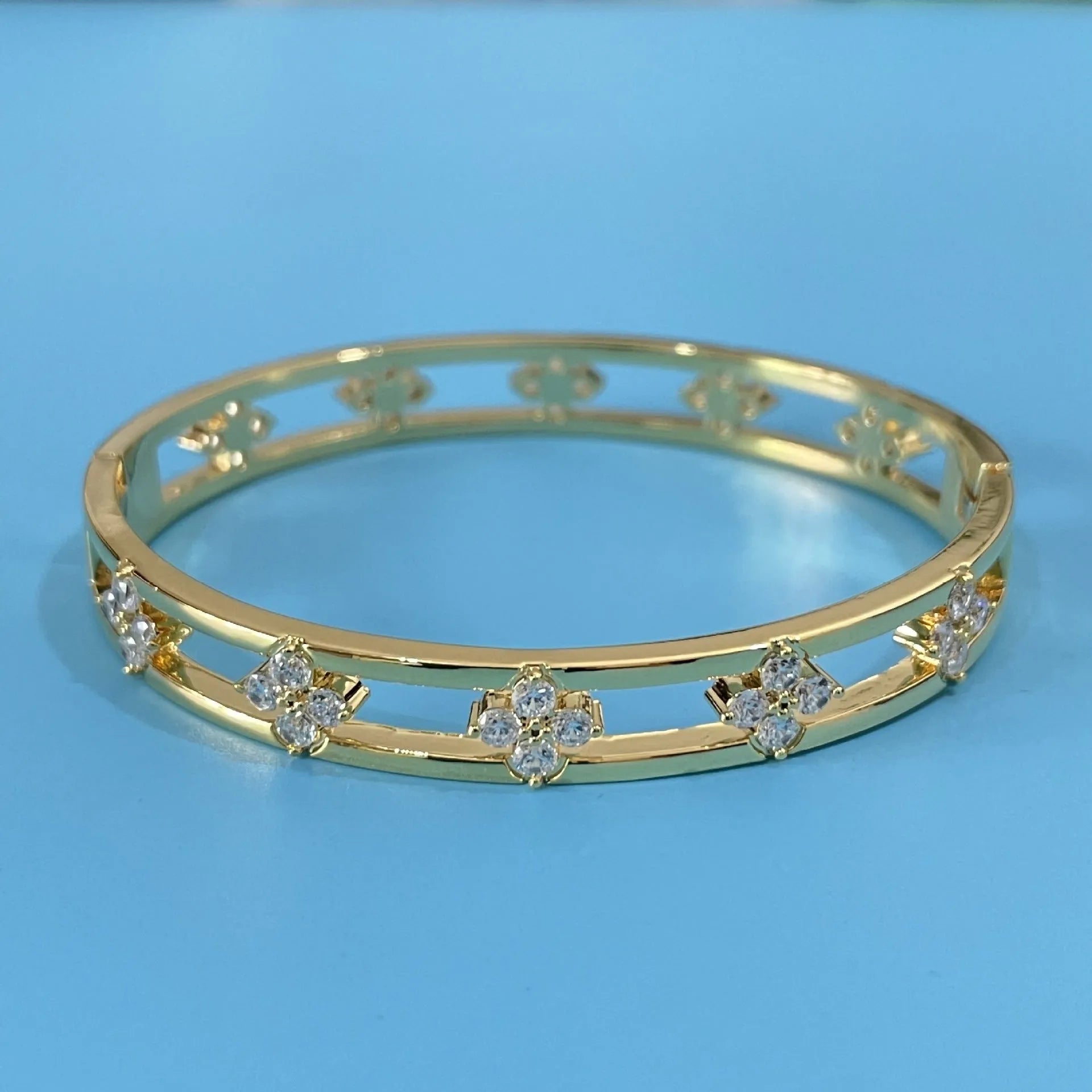 Women's hollow bracelet with four-leaf clover charm and zircon inlay detailing on copper-plated gold