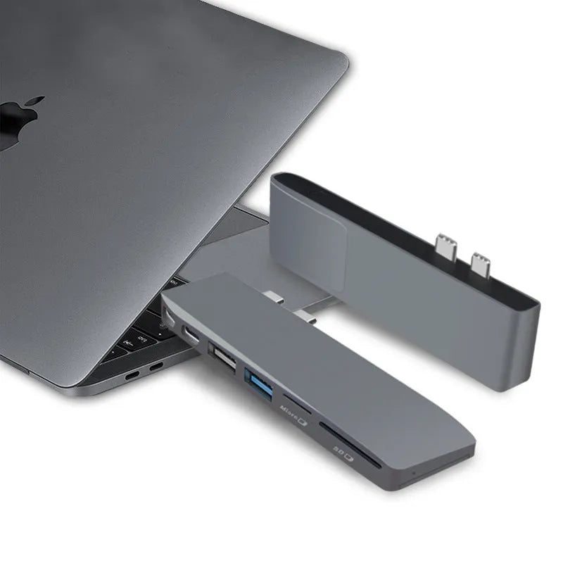 Silver USB-C hub with multiple ports for MacBook Pro, showing USB, card slots, and charging port