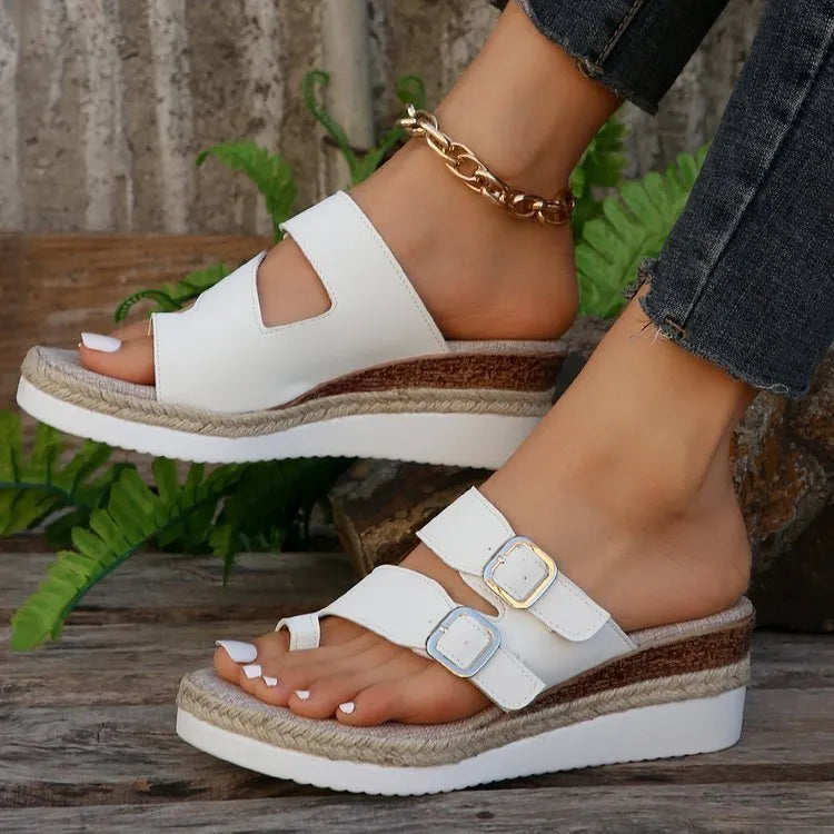 White patent leather woven wedge sandals with a peep toe and finger fit design on a neutral background.