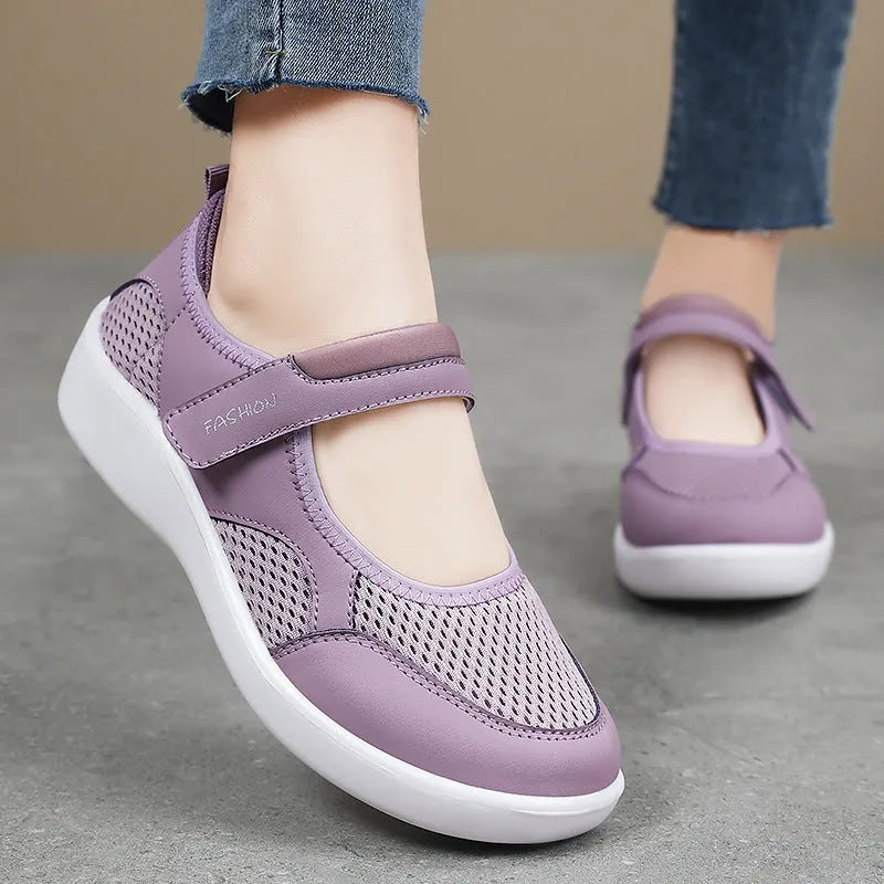Women's grey casual slip-on shoe with mesh upper and Velcro strap on a flat sole.