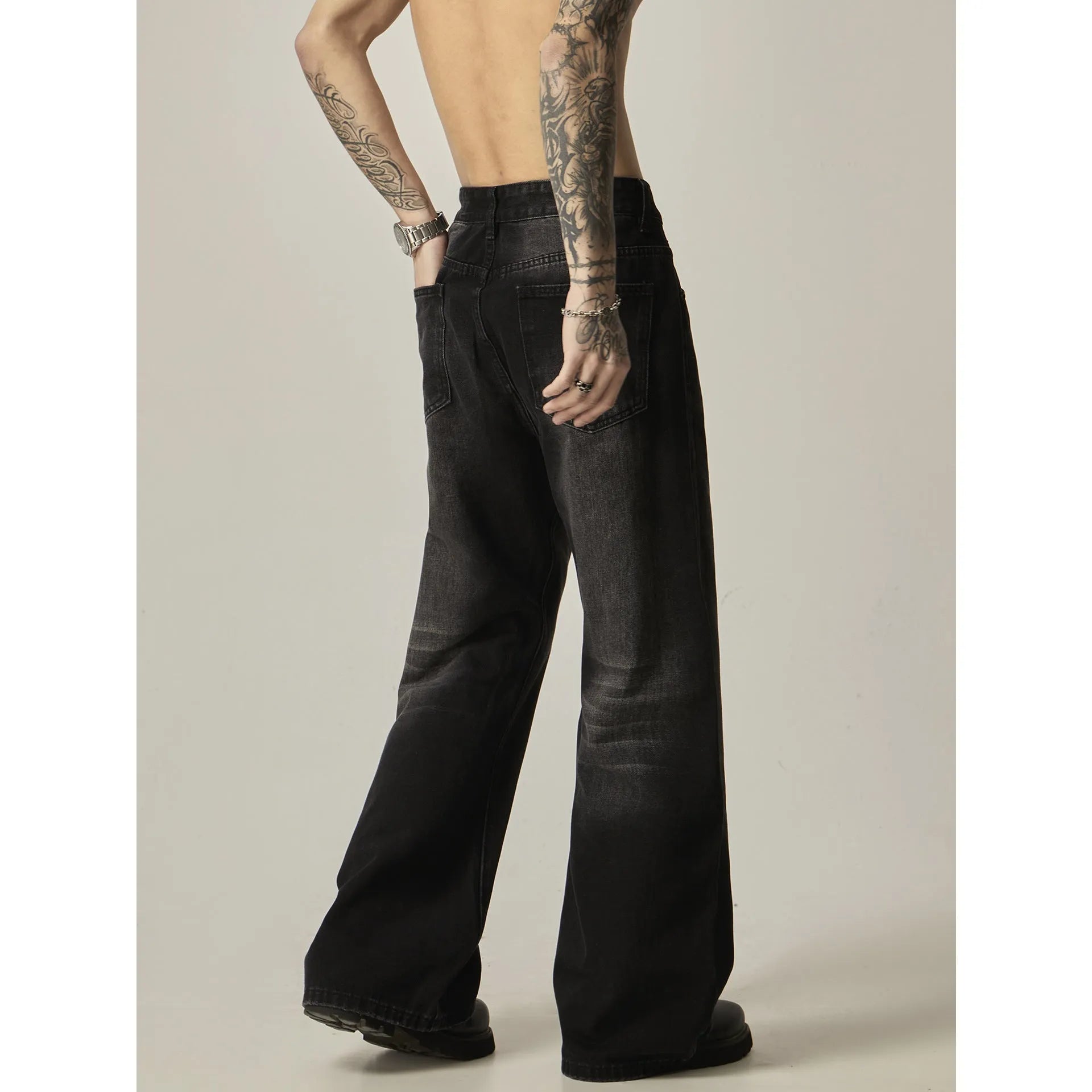 Black loose straight-leg retro jeans on a hanger, showing the front view with zipper fly.