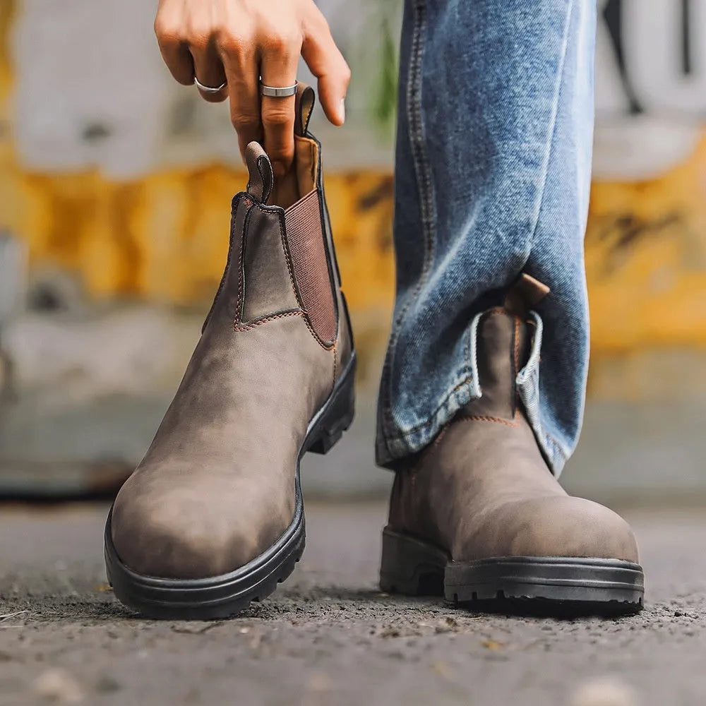 Vintage brown unisex Chelsea boot with frosted PU upper and round toe on a wooden surface.