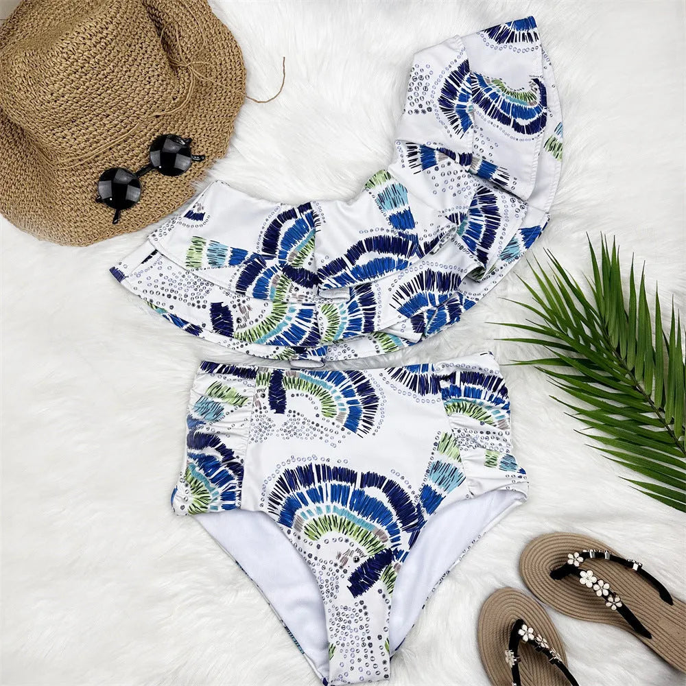 White women's one-shoulder swimsuit showing double-layer lotus leaf detail and a high side leg split.