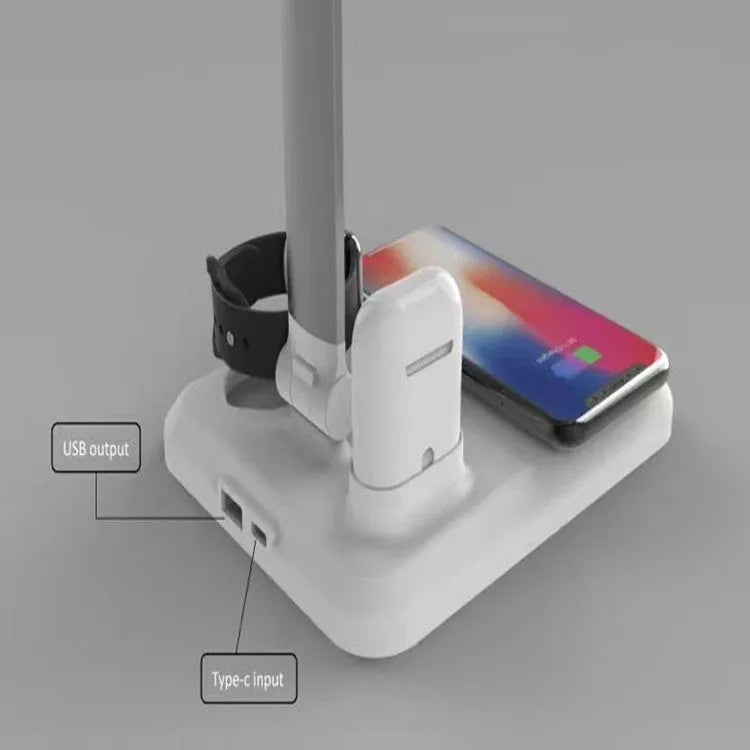 Black and white 4-in-1 LED desk lamp on a desk, showing wireless charging area and USB-C port.