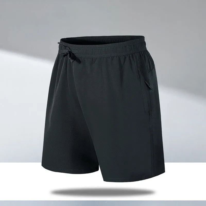 Man wearing loose fit black quick-dry sports shorts on a beach.