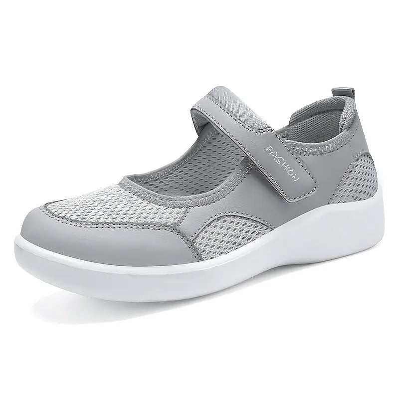 Women's grey casual slip-on shoe with mesh upper and Velcro strap on a flat sole.