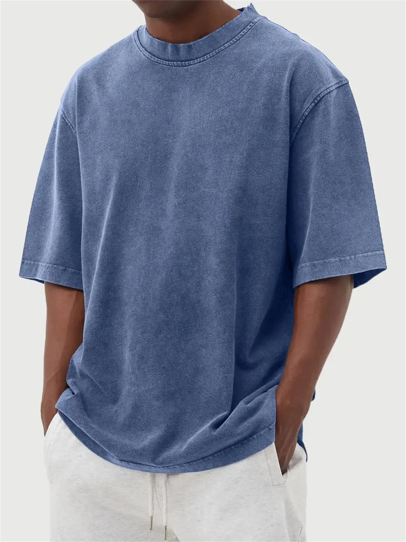 Man wearing a loose-fit, stone-washed distressed pullover T-shirt in a solid colour.
