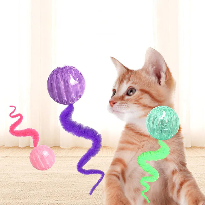 Interactive cat toy with purple bouncy ball and plush tail on wooden floor