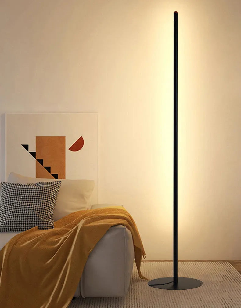 Modern simple vertical aluminium alloy floor lamp in silver, shown beside a sofa.