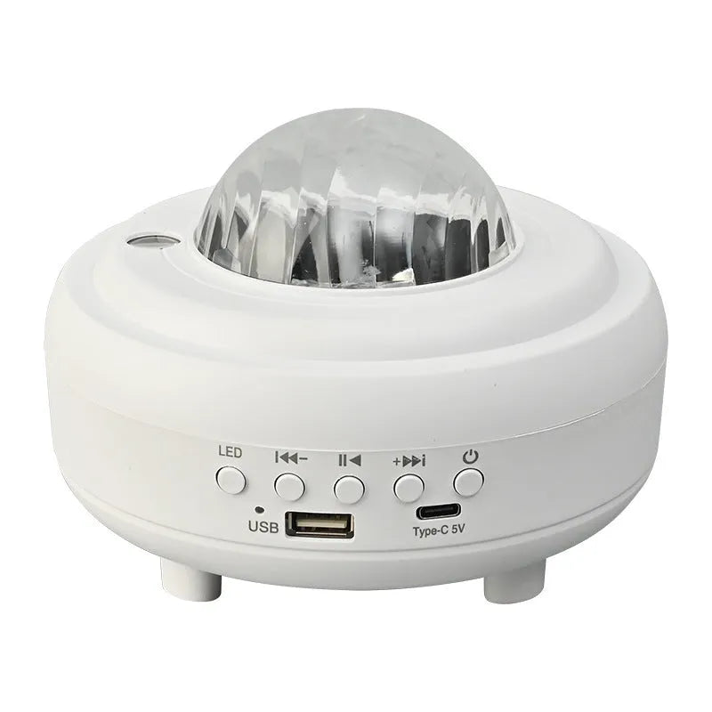White and black rechargeable galaxy star projector night light with Bluetooth speaker on a table.