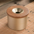 Brass ashtray with wooden lid showing central hole design for ash collection