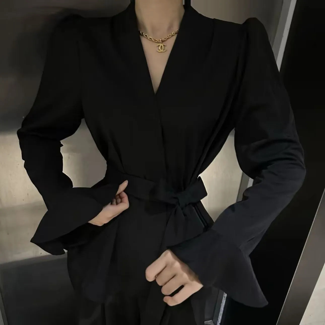 Women's black long sleeve shirt with irregular French collar, front tie, and bell sleeves