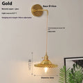 Retro brass copper lotus wall lamp with a glass shade in one of six colours, shown beside a bed.