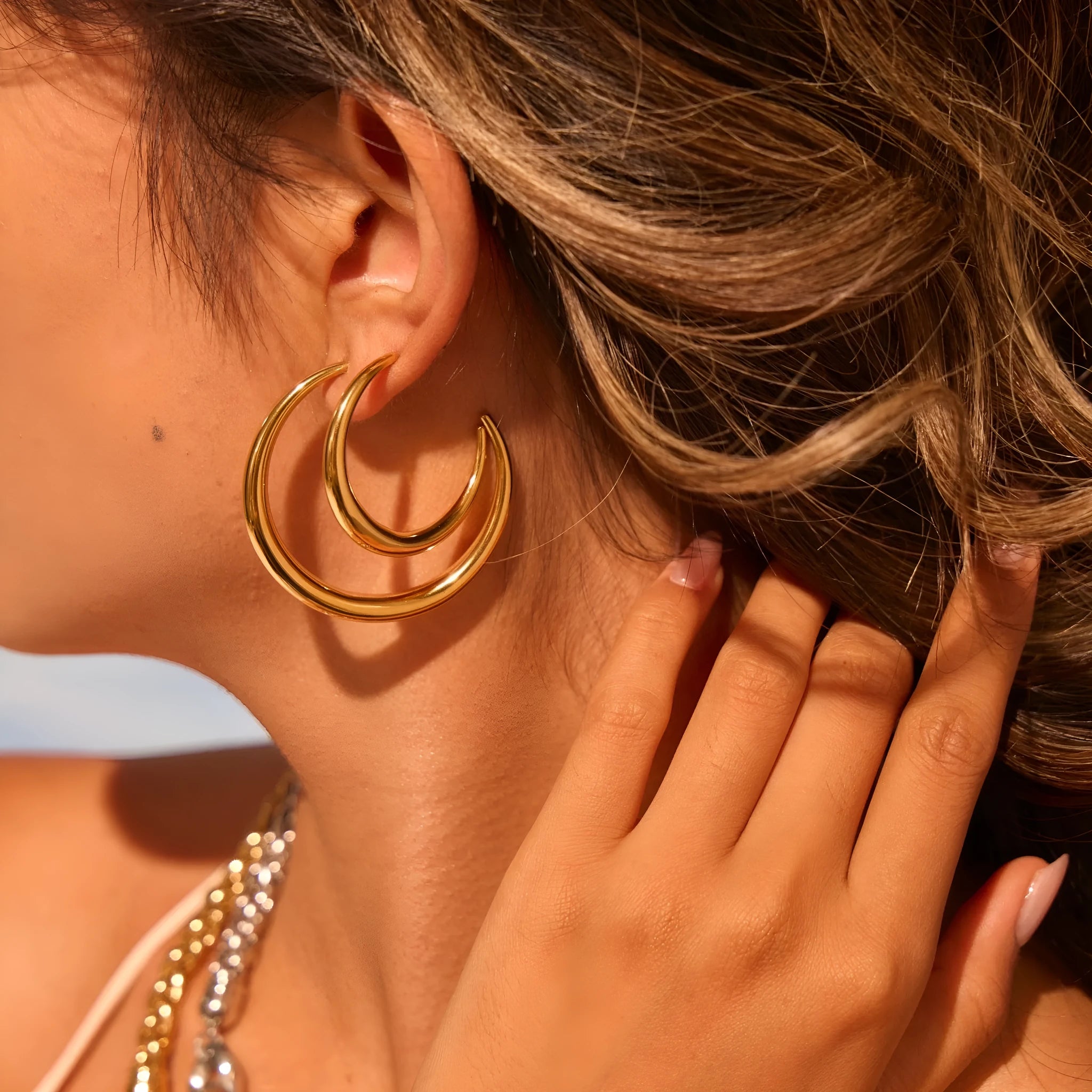 A pair of simple round titanium steel hoop earrings in a gold finish on a white background.