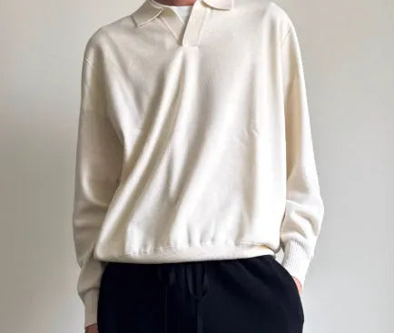 Man wearing a milky white pure wool polo sweater with a lapel collar and loose long sleeves.