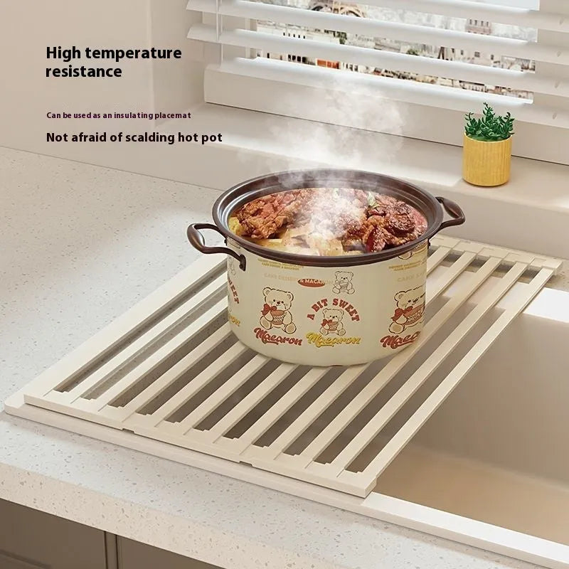 A milky white foldable stainless steel kitchen draining rack shown open on a countertop next to a sink.