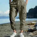 Man wearing loose-fit linen casual trousers with ankle-tied cuffs and multiple pockets in a solid colour.
