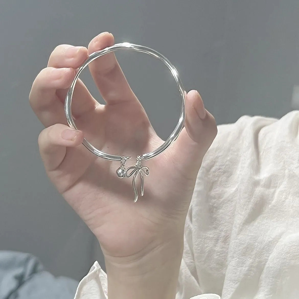 Silver adjustable bracelet with a large bow-shaped clasp on a white background.