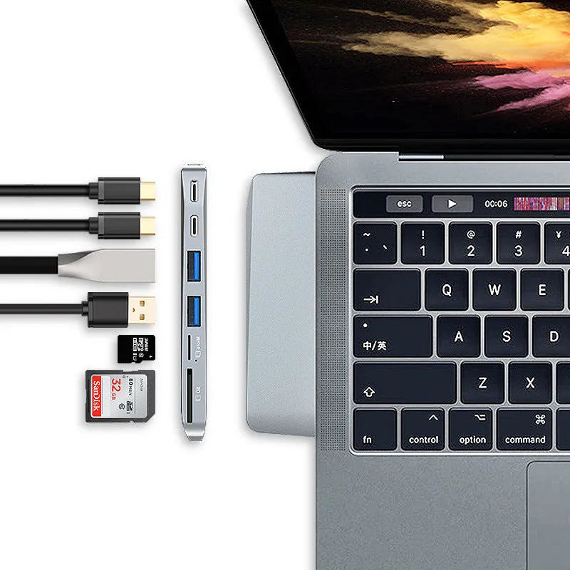 Silver USB-C hub with multiple ports for MacBook Pro, showing USB, card slots, and charging port