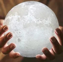 3D printed spherical moon lamp with textured surface on a wooden stand, showing white LED light.